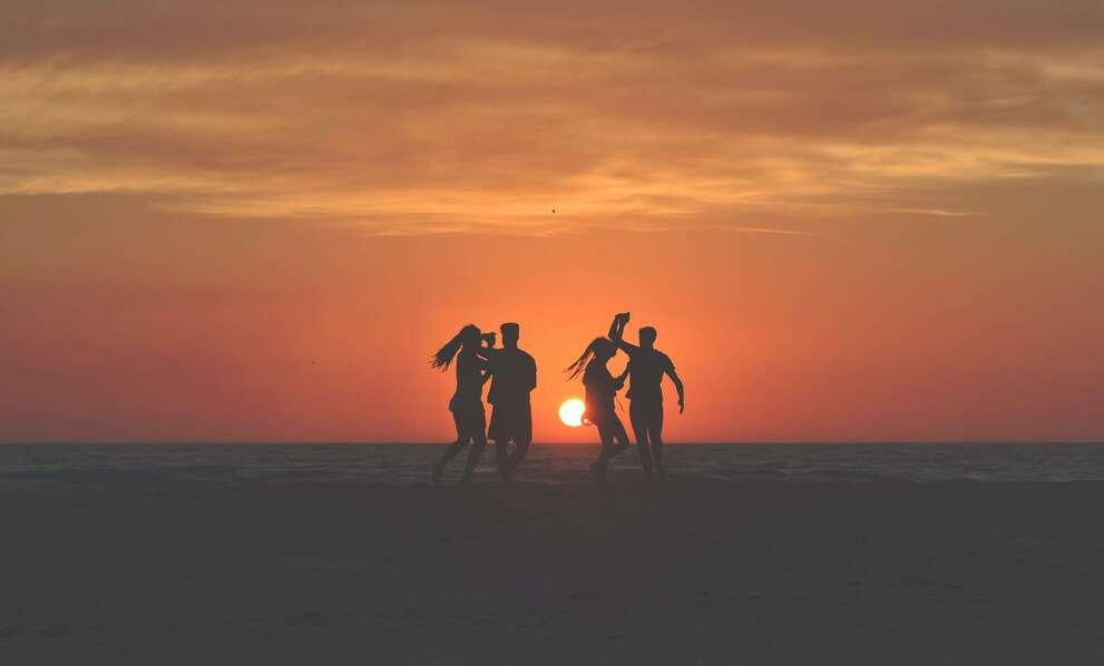 Silhouettes dansant sur la plage au coucher du soleil